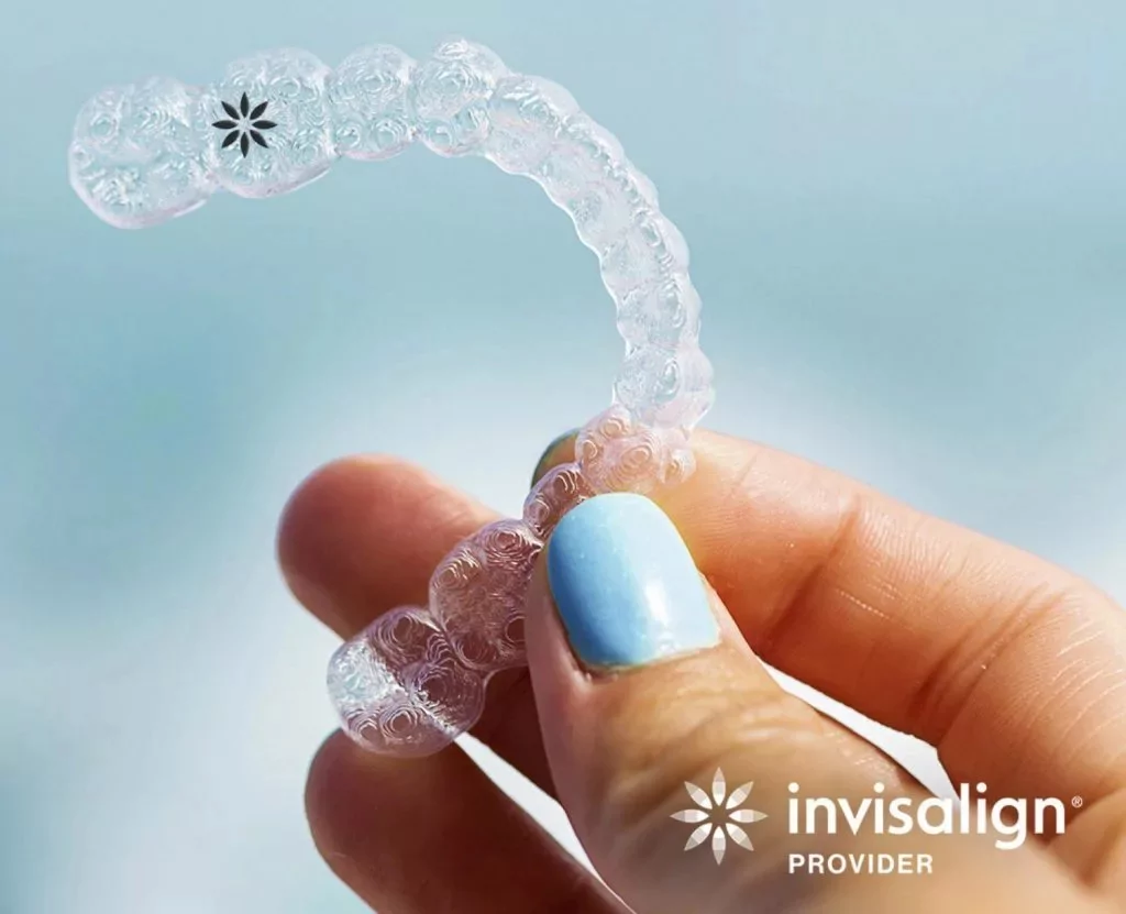 Hand holding an Invisalign brand clear aligner.