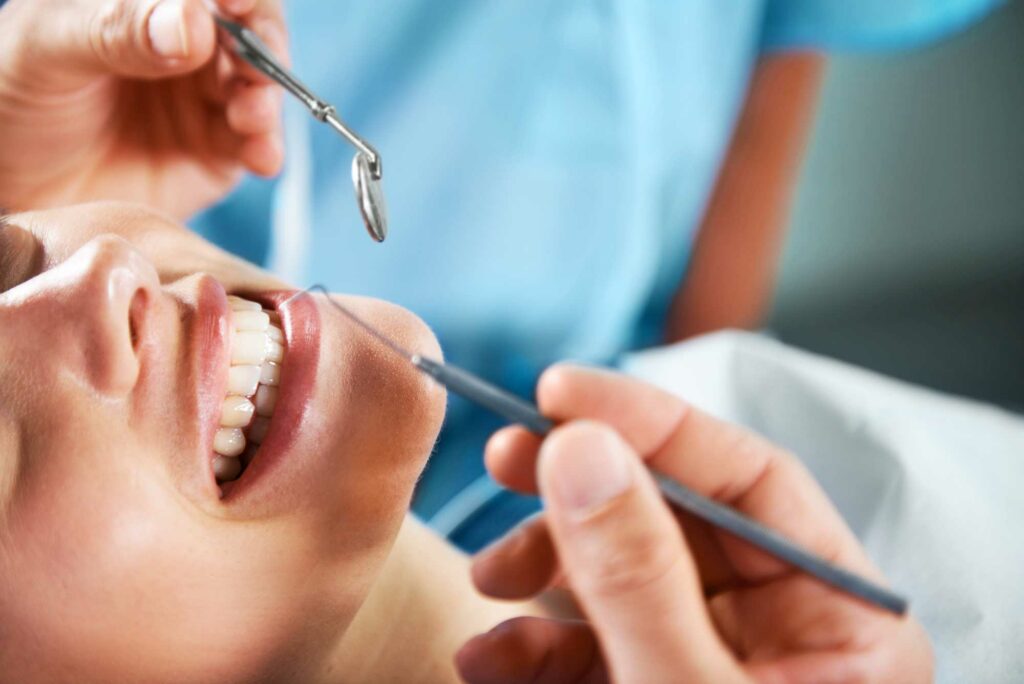 patient smiling while laying in dental chair with dentist about to check teeth