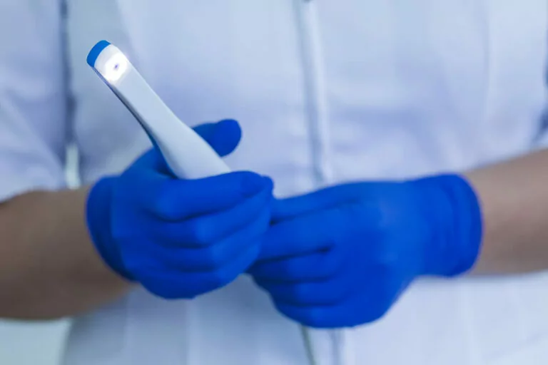 Doctor's hands holding an intraoral camera, a dental device used to investigate issues in the mouth.