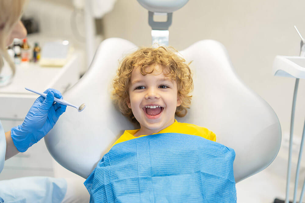 Little boy smiling in a dental exam chair.
