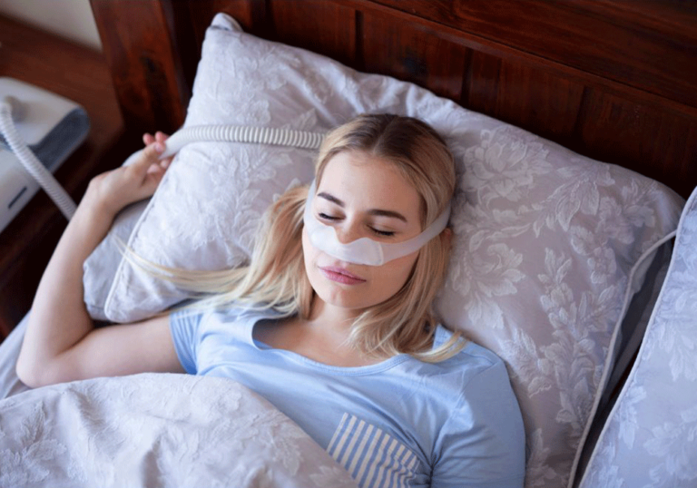 Young woman sleeping with a CPAP machine to correct her sleep apnea.