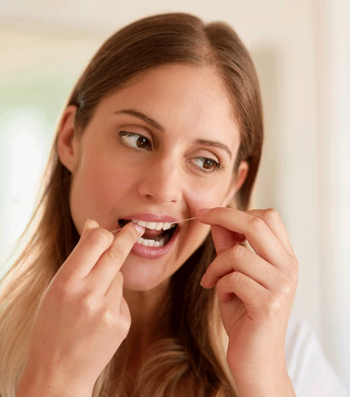 Photo of a woman flossing her upper row of teeth.